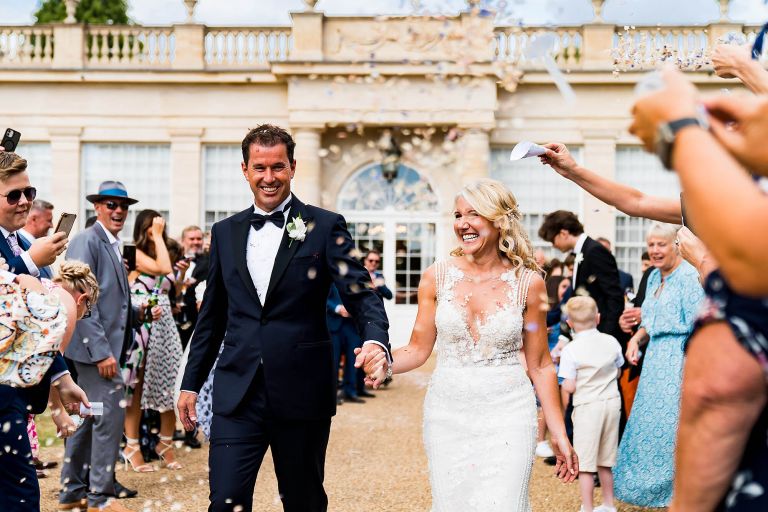 Confetti and bride with groom in front of orangery 