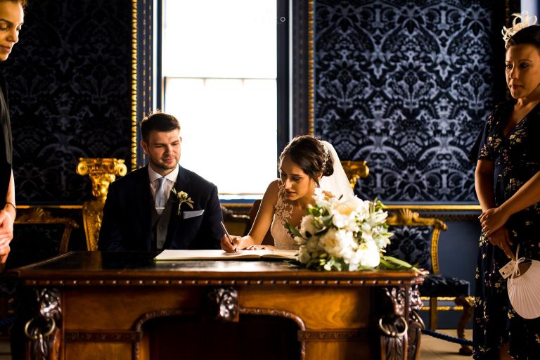 bride and groom signing register London Wedding Chiswick house