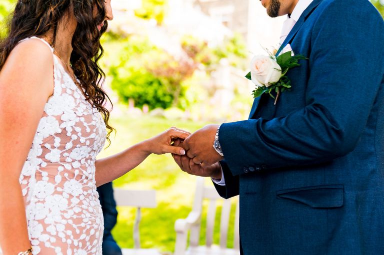 The groom is putting ring on the brides finger detail photo
