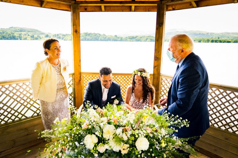 Bride and groom signing the register in pergola at Langdale Chase hotel