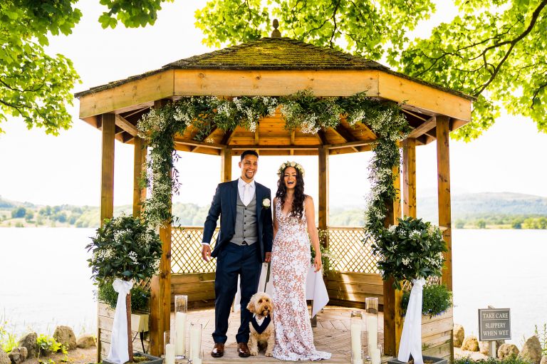 The bride and groom and their dog laughing 