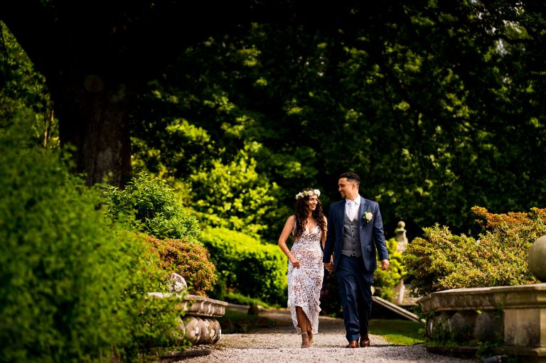 Freshly married couple walking and laughing in the gardens at lake district 