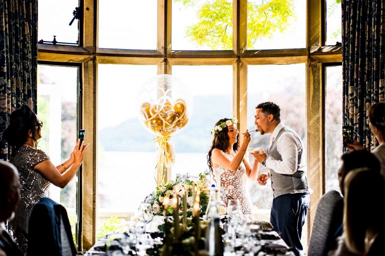 Bride is feeding the groom with the wedding cake